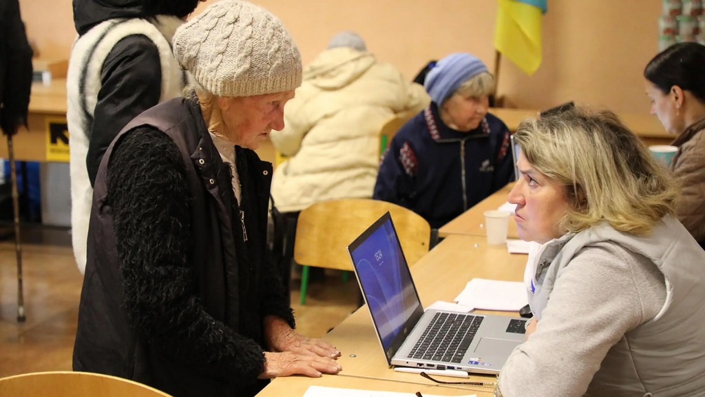 An aid worker registers an evacuated woman for multi-purpose cash assistance at the transit centre.